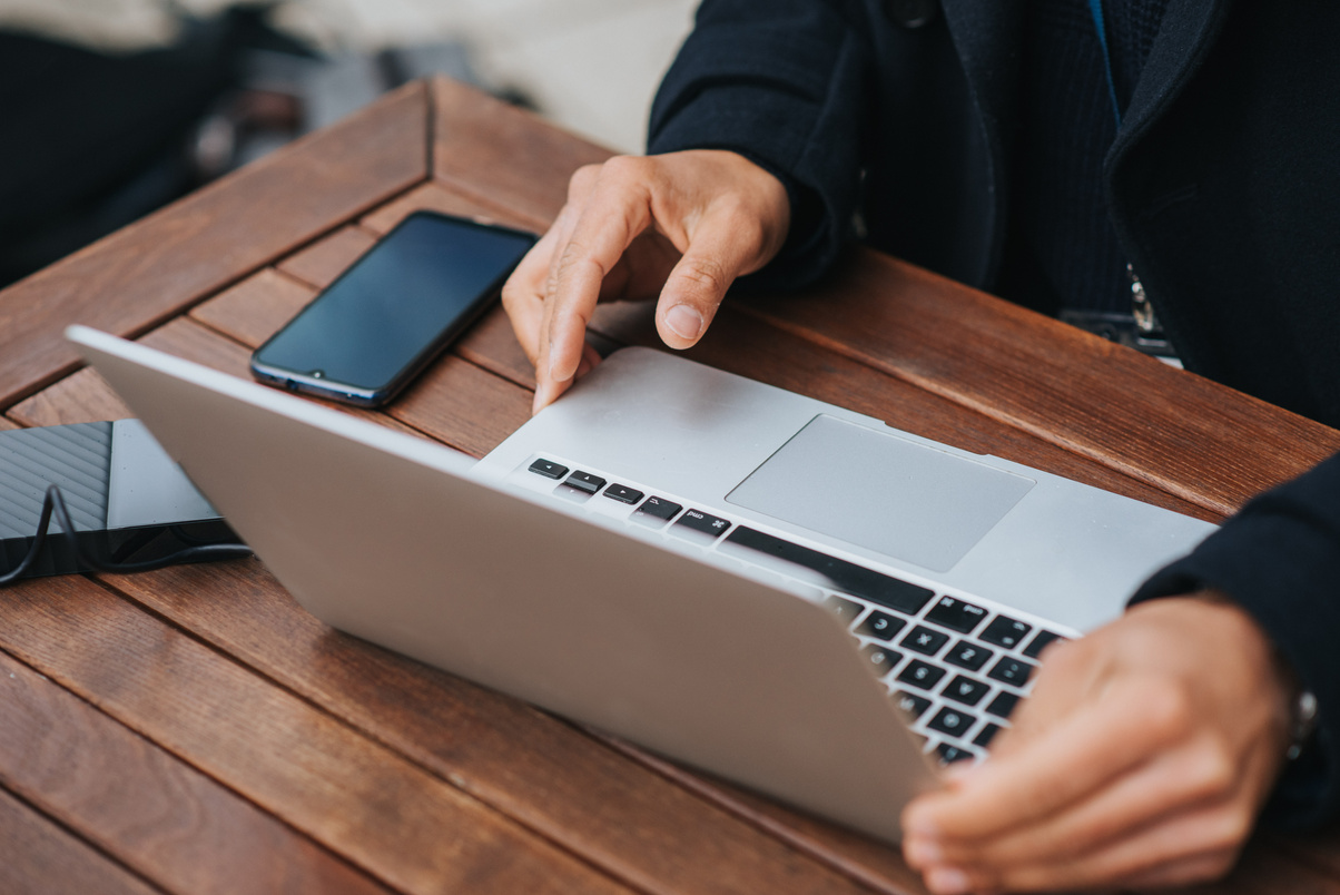 Crop manager with laptop and smartphone in street cafe